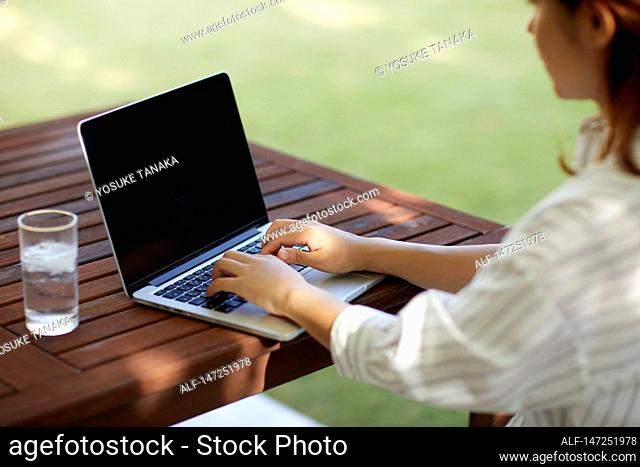 Japanese woman working with laptop in the garden