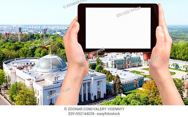travel concept - tourist photographs Verkhovna Rada building (Supreme Council of Ukraine) and Mariyinsky palace in Mariinsky park in Kiev city on tablet with...