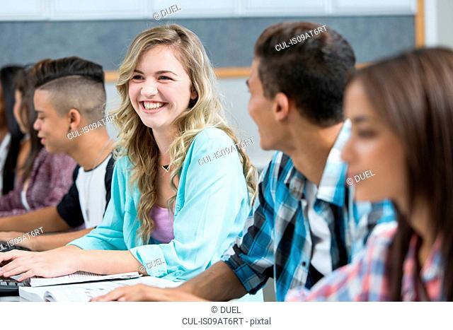 Row of teenage high school students smiling in computer class