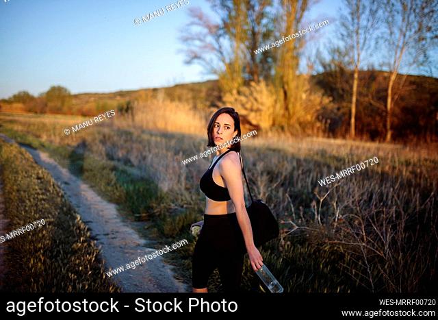 Sportswoman with bag looking over shoulder while leaving after sports training