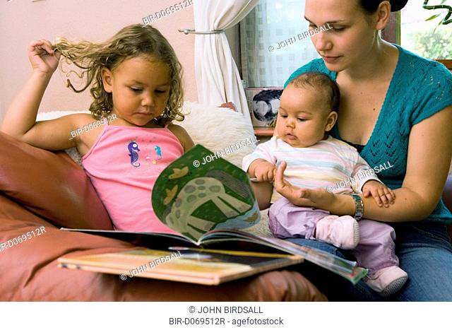 Mother reading a book with her young children