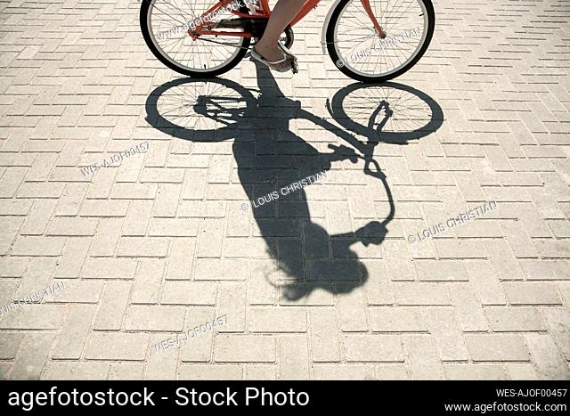 Leg of woman cycling on promenade during sunny day