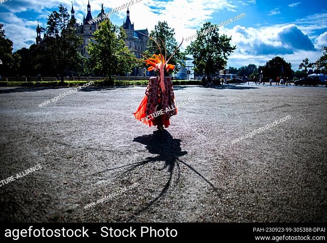 23 September 2023, Mecklenburg-Western Pomerania, Schwerin: Wearing a colorful costume and a hat with the St. Mark's Tower