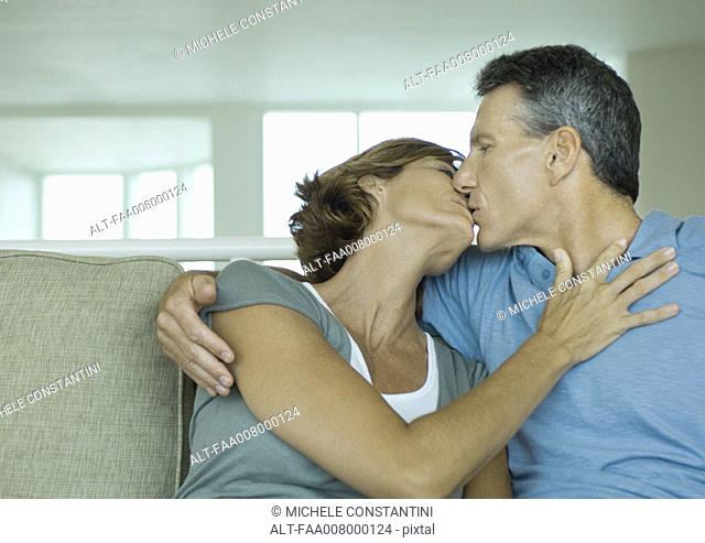 Mature couple kissing on sofa