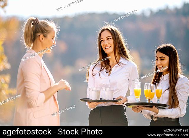 Waitress standing with drinks tray looking at businesswoman