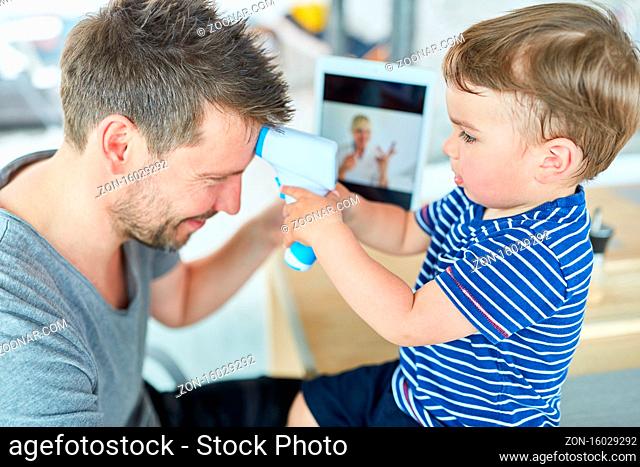 Junge beim Fieber messen beim Vater in der Online Sprechstunde im Videochat