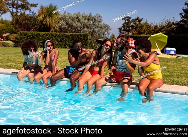 Diverse group of friends talking and sitting at the poolside