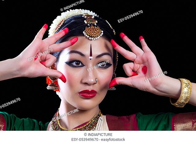 Close-up of young woman making Bharatanatyam gesture called Shakatam on black background