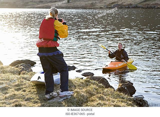 A woman photographing a man in a canoe