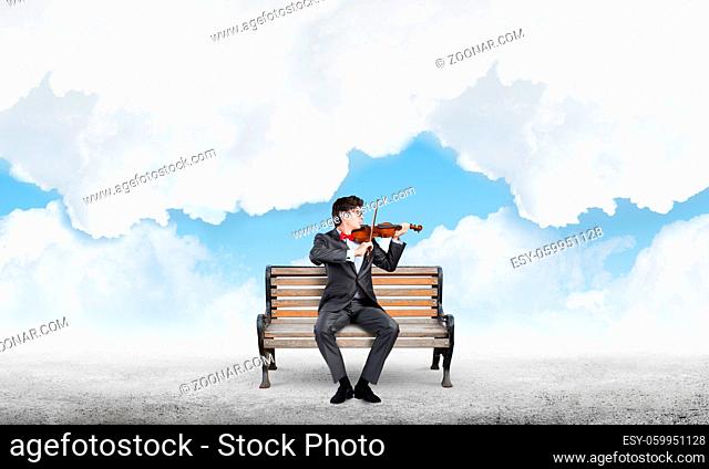 a young businessman plays the violin. sits on the bench