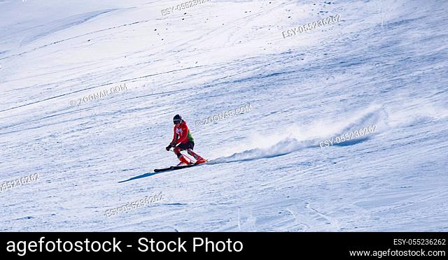 skier riding down the huge snowfield splashing powder snow