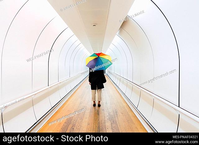 Young woman with umbrella standing on walkway