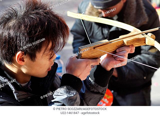 Beijing (China): a young man playing with a crossbow at the Dongyue Temple during the Spring Festival