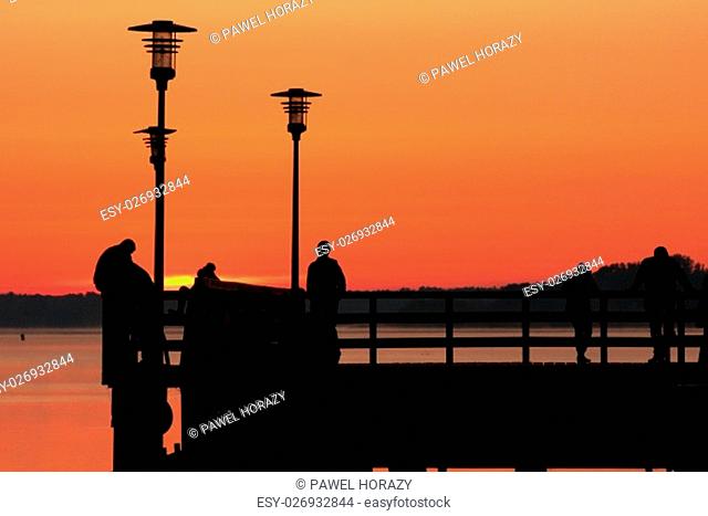 silhouettes of people standing on the dock early in the morning and waiting for sunrise