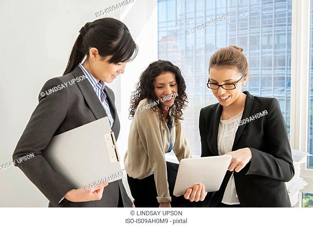 Three businesswomen sharing ideas on digital tablet