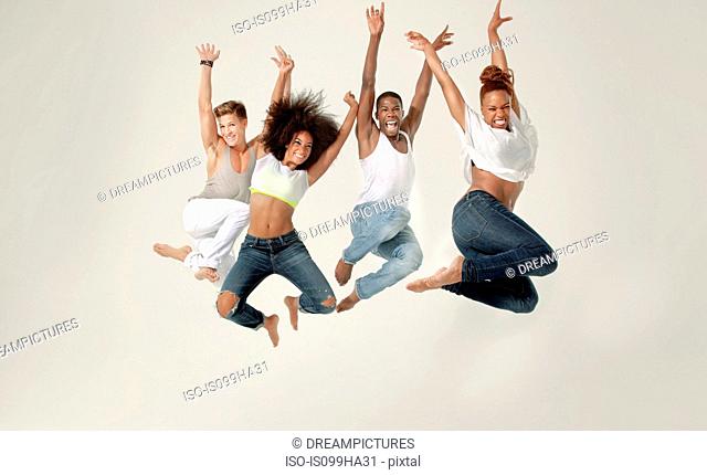 Four young adults jumping in the air with joy