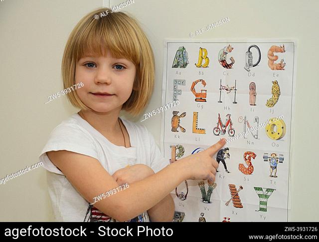 Girl, 6 years old, shows a poster with alphabet in Ystad, Scania, Swedden, Scandinavia
