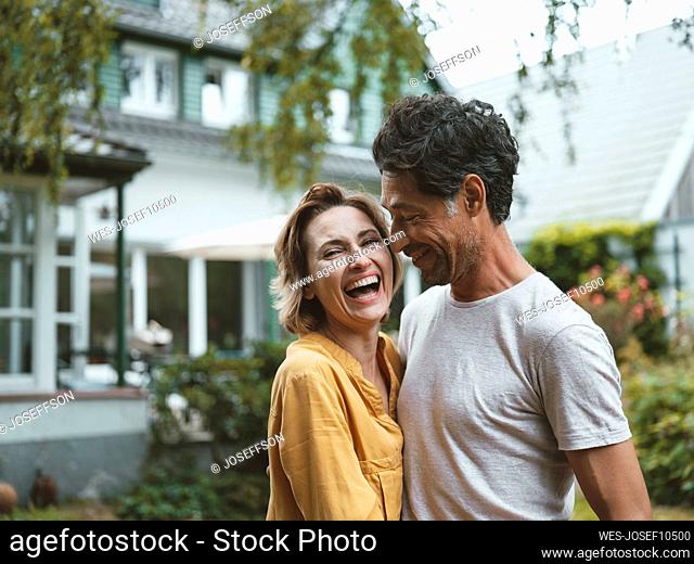 Cheerful mature woman with man standing in front of house