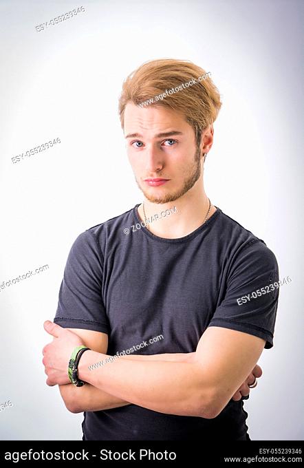 Sad or worried handsome young man looking down, on light background