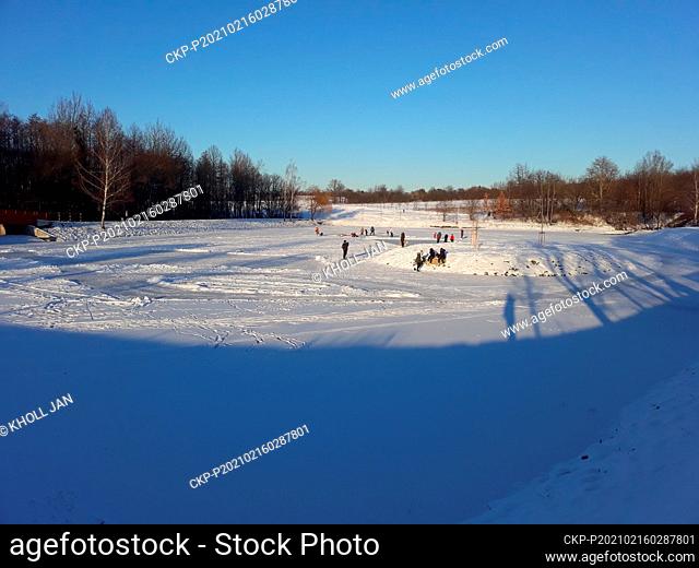 People enjoy the sunny wintry weather and winter sports on the frozen pond Rozpakov in Ricany, Czech Republic, February 15, 2021