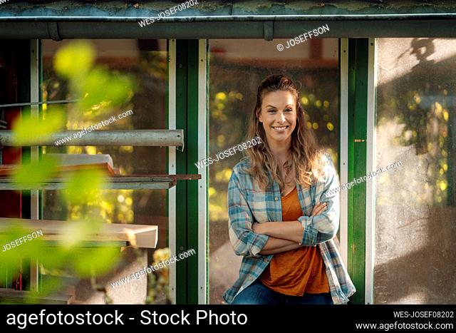 Smiling blond woman with arms crossed standing in front of glass window