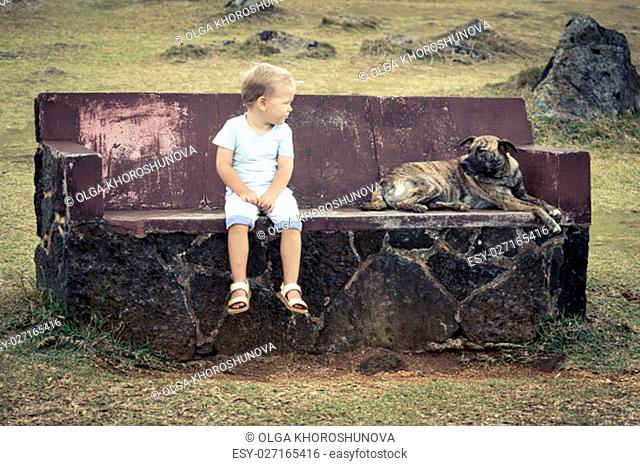 Child and dog are sitting on a bench