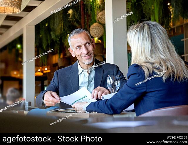 Businessman showing document to client in meeting at restaurant