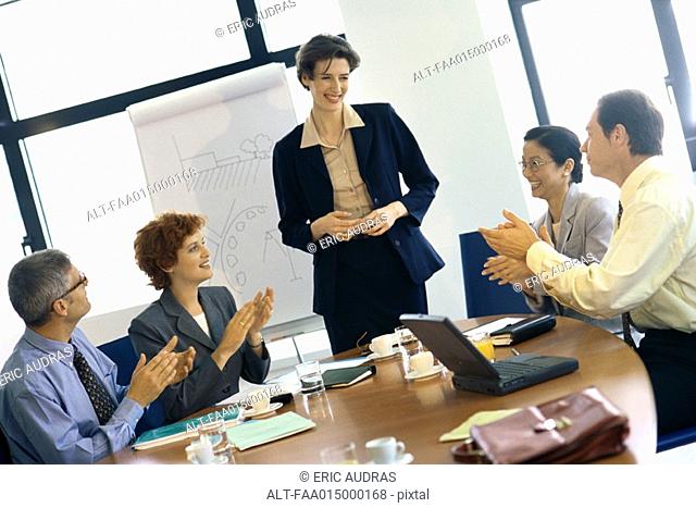 Colleagues clapping for businesswoman after presentation