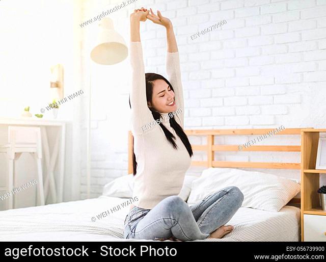 Beautiful young woman stretching and waking up in the bedroom