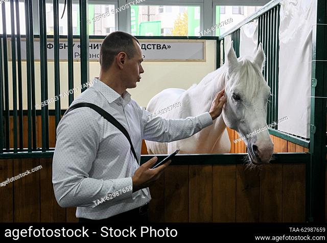 RUSSIA, MOSCOW - OCTOBER 4, 2023: A man pets a horse at the 2023 Golden Autumn agricultural exhibition held at the Russian State Agrarian University – Moscow...