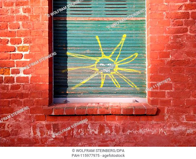 22.10.2018, Potsdam: Eine lachende de Sonne ist mit gelber Kreide auf einen grünen Rolladen aus Holz an einem Fenster gemalt