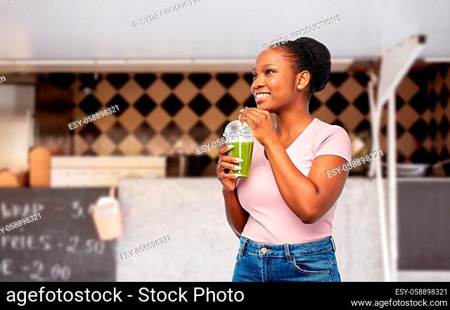 happy african american woman drinking green juice