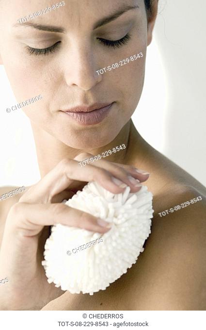 Close-up of a mid adult woman scrubbing her body with a scrubber