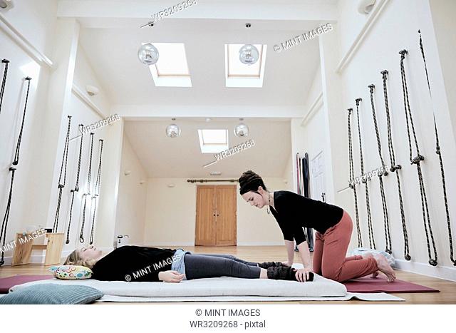 Woman lying down fully clothed having a Thai massage in a light filled exercise studio