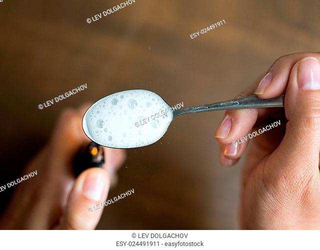 drug use, crime, addiction, substance abuse and people concept - close up of addict hands with lighter and spoon preparing dose of crack cocaine on street