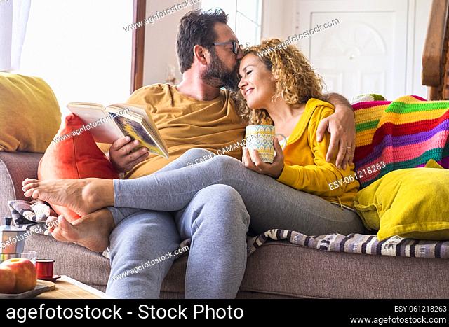 Happy beautiful caucasian couple at home enjoy morning leisure activity in relax together - love and relationship life with young people sitting on the colorful...