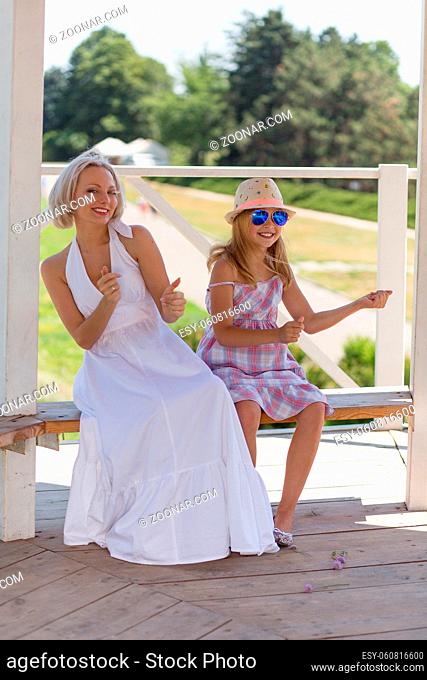 Mom and daughter in playful mood. Young blond lady having fun with her child girl