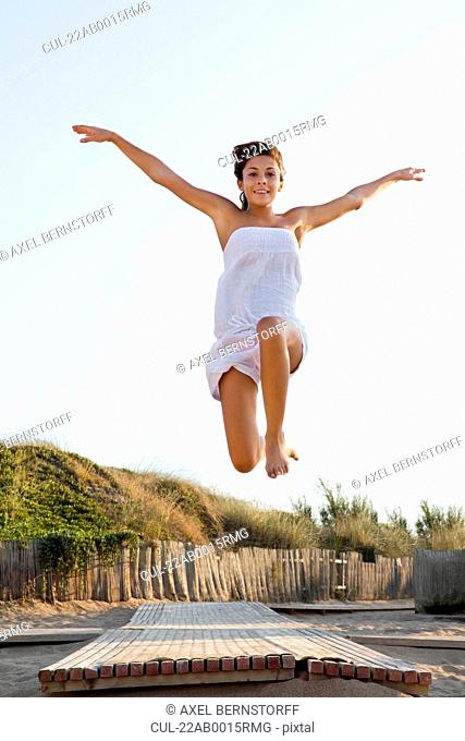 Happy woman jumping over jetty