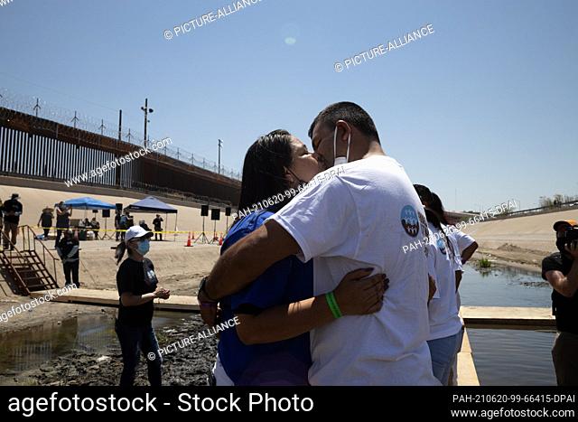 19 June 2021, Mexico, Ciudad Juarez: Two people kiss at the border wall between Mexico and USA during the action ""#HugsNotWalls"" of the NGO Border Network for...