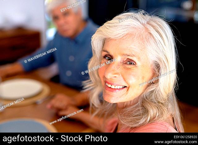 Close-up portrait of smiling caucasian senior woman holding biracial man's hand at dining table