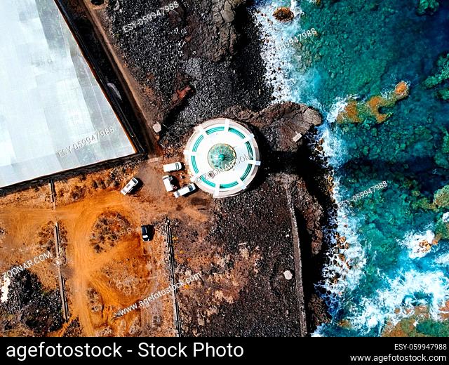 Aerial top view of lighthouse, rocks and ocean waves in a volcanic landscape with lava. Punta Lava Lighthouse in La Palma