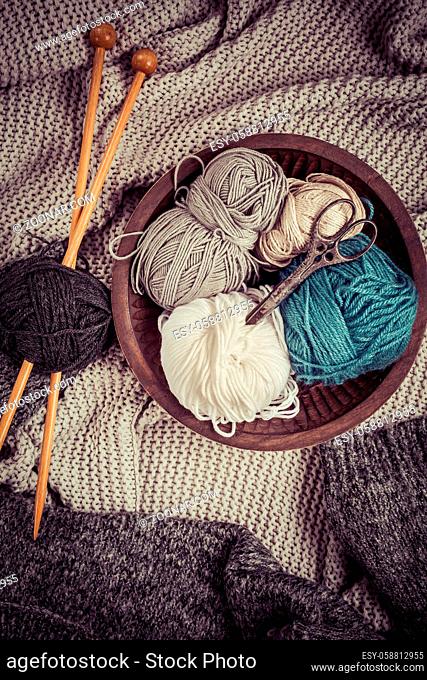 Home life - Knitting concept, knitting needles with blanket, scissors and yarn in wooden bowl