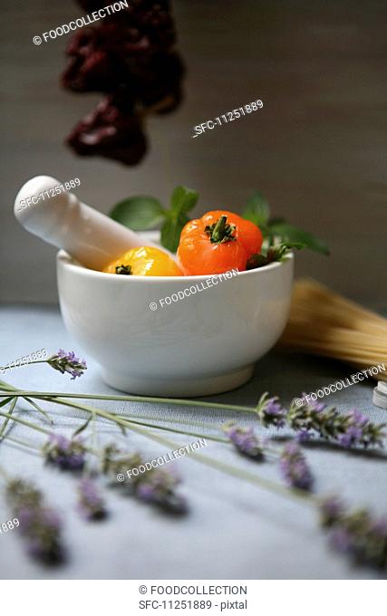 An arrangement featuring white mortar, lavender and fresh and dried peppers