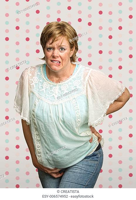 Uneasy pregnant woman with pains on polka dot background