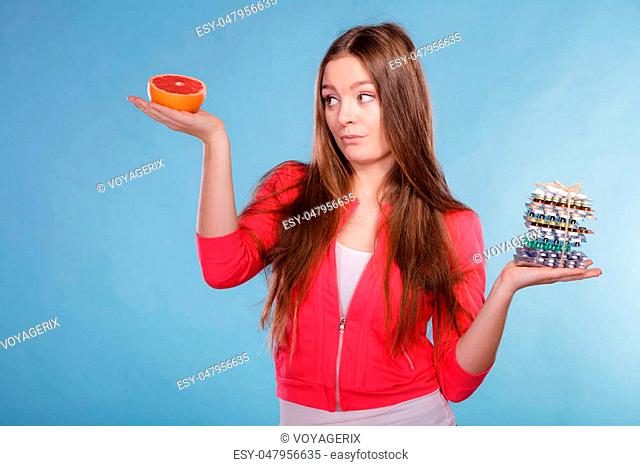 Woman girl holding diet weight loss tablets pills and grapefruit. Choice between natural and synthetic way of slimming dieting. Health care