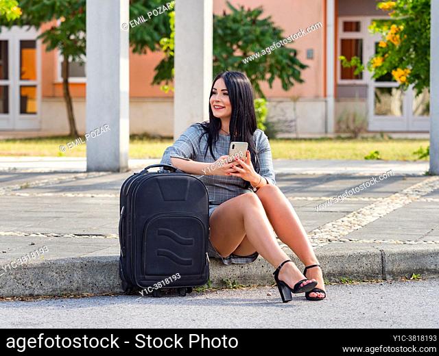 Young woman is going traveling sitting on roat street sidewalk