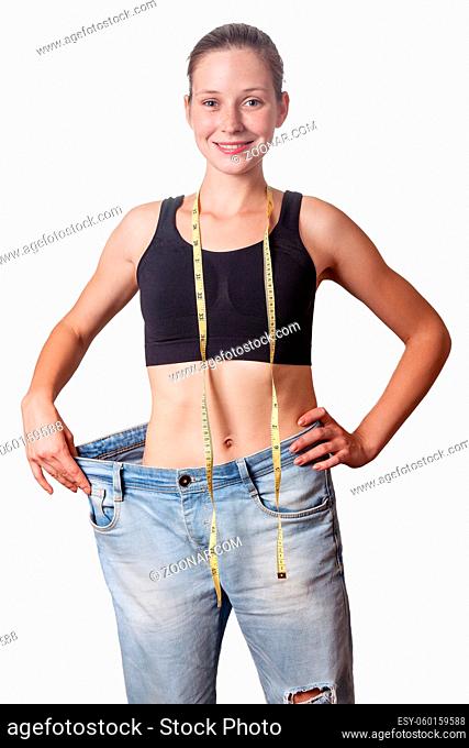 Close-up of slim waist of young woman in big jeans showing successful weight loss, isolated on white background, diet concept