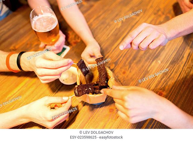 fast food, junk food, unhealthy eating and culinary concept - close up of people hands taking garlic bread snack with skewers at bar or restaurant
