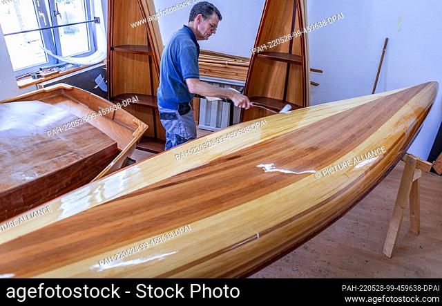 19 May 2022, Mecklenburg-Western Pomerania, Peenemünde: Ulrich Stenberger from Raubling near Rosenheim paints his canoe two-seater