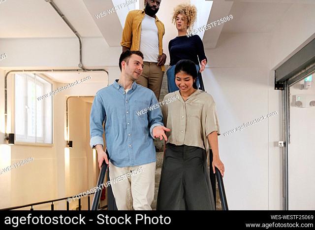 Group of business people descending stairs in modern office